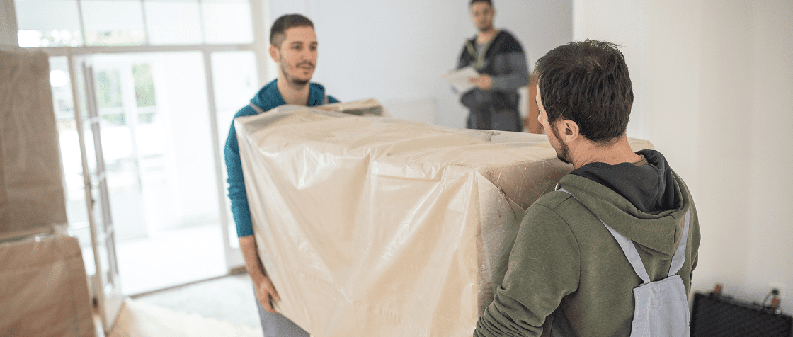Team lifting a packaged furniture piece