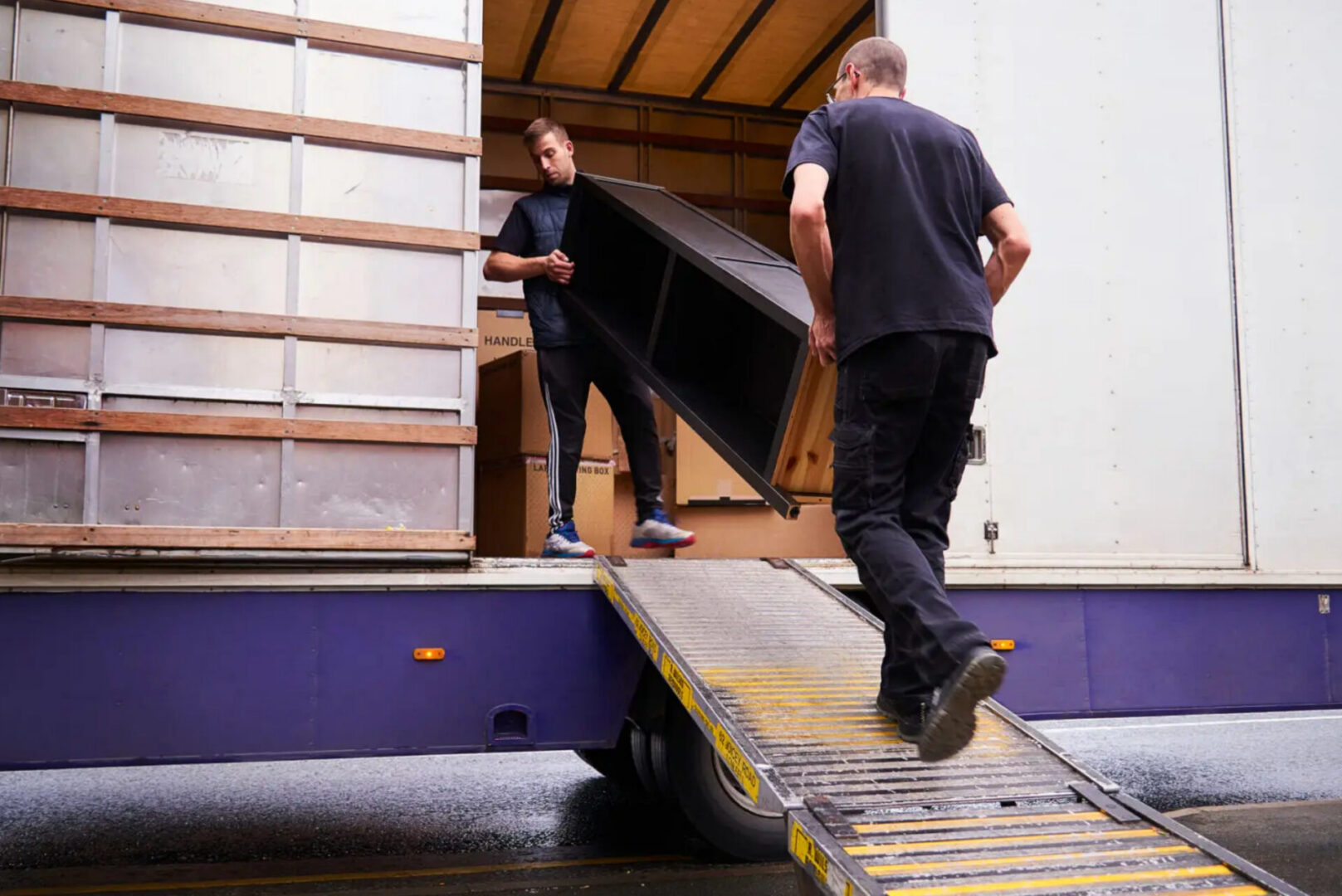 Two movers loading furniture into moving truck