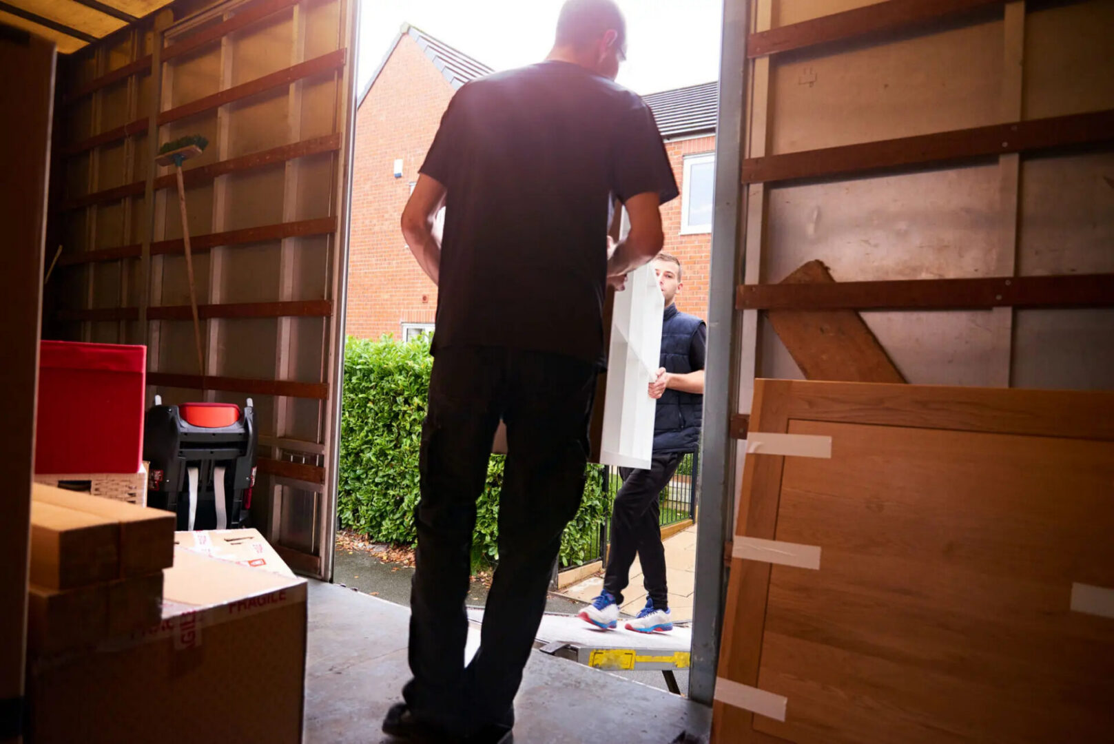 Two movers carrying furniture into moving truck