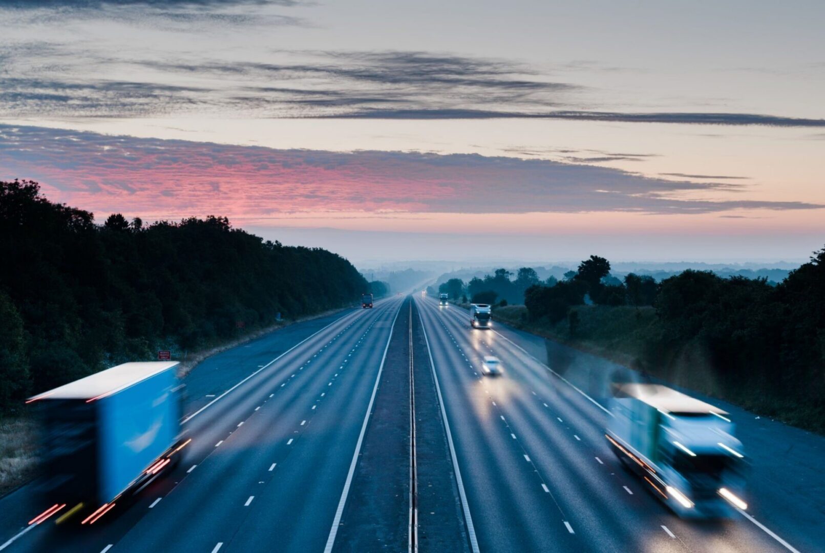 Blurred trucks speeding on highway at sunset