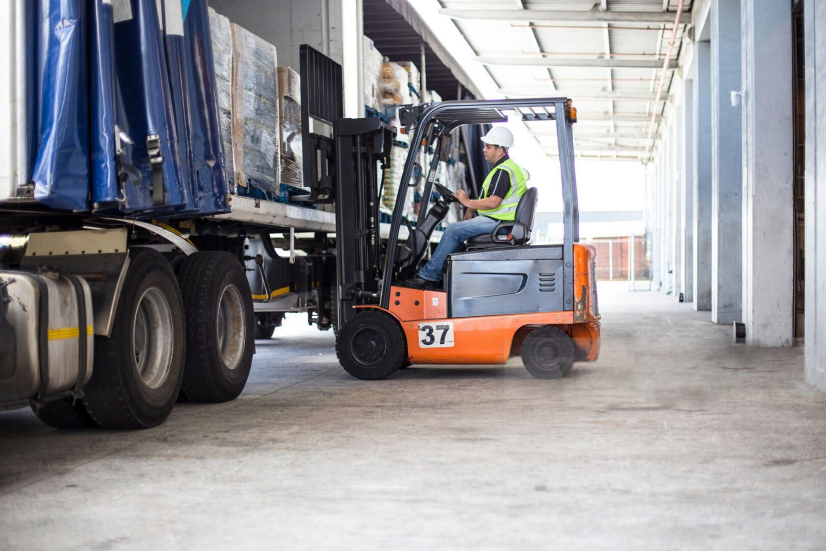 Forklift loading pallets into truck at warehouse