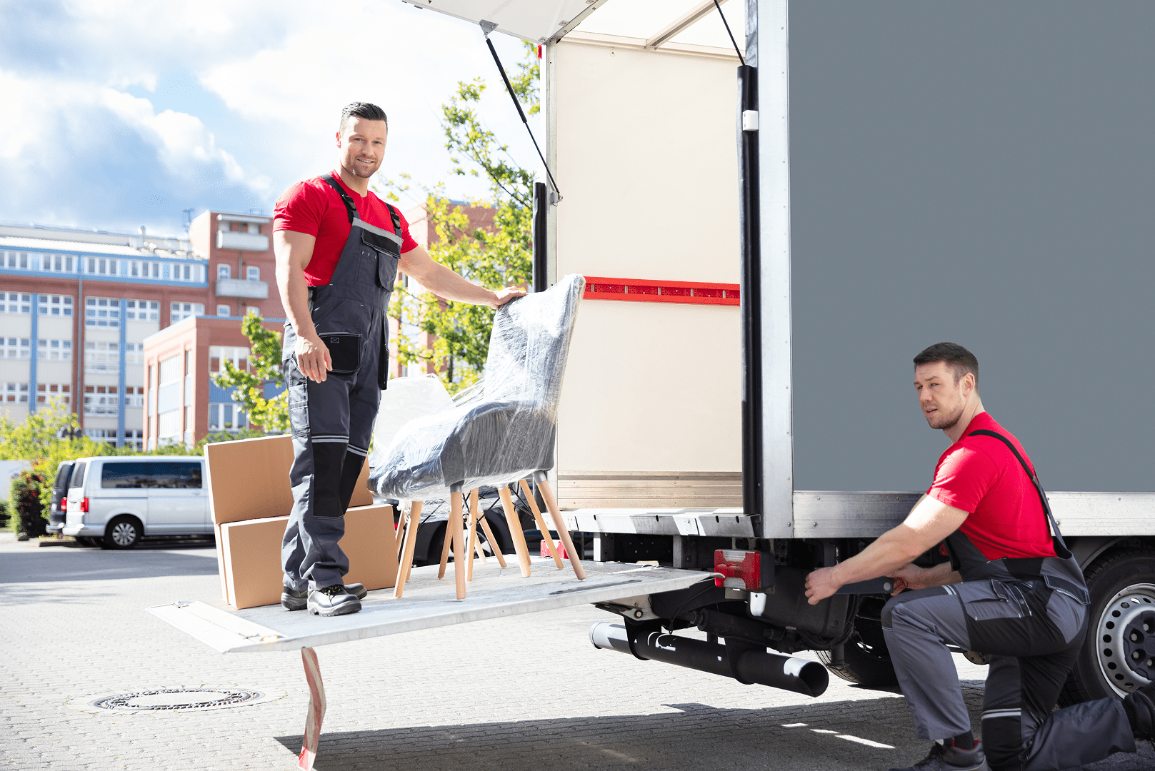 Two movers loading wrapped chairs into moving truck