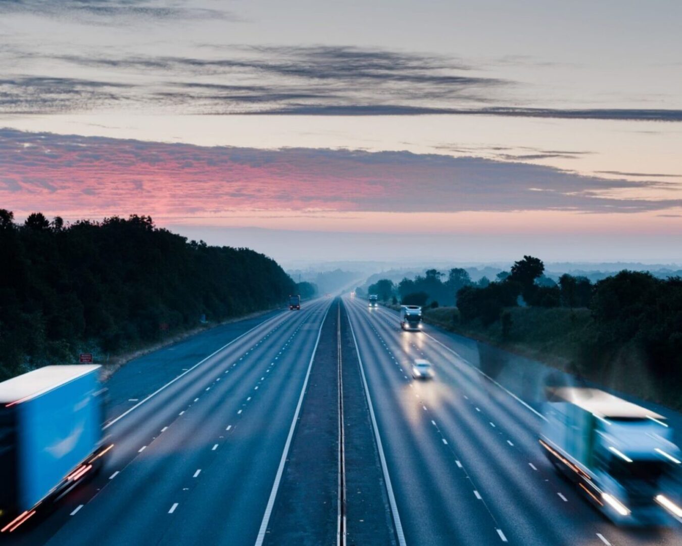 Blurred trucks and cars on highway at dawn